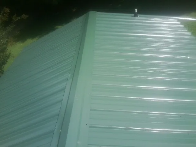 New green metal panels meeting at the ridge of a roof — Flat Roof Repair work by our crew in Woodland Hills