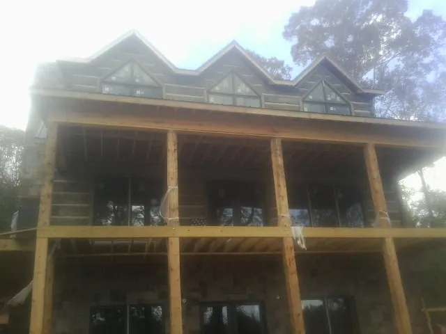 Dormers and porch framing on a large log home under construction — Roof Coating work by our crew in Woodland Hills
