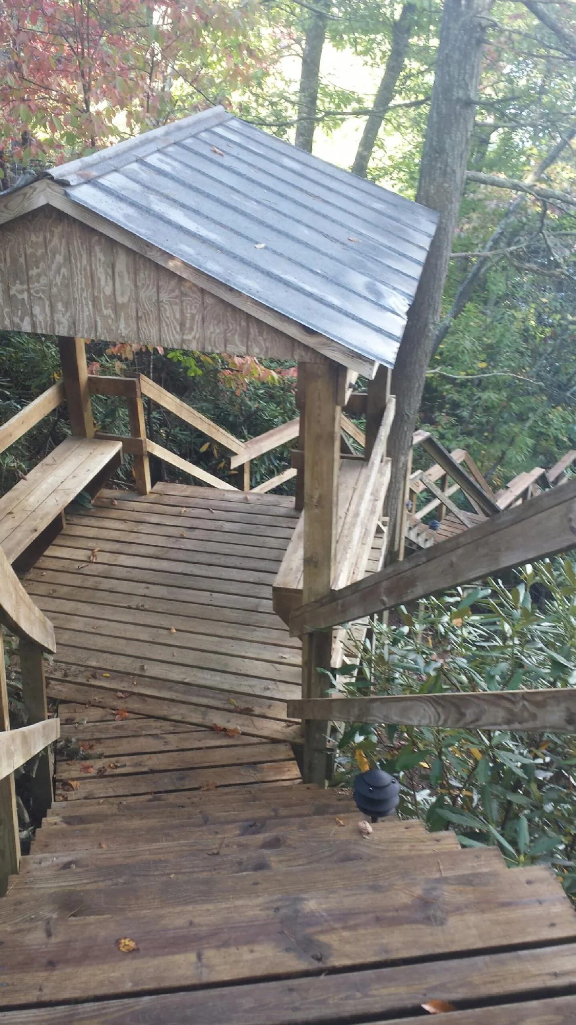 Metal roofed shelter over wooden steps on a wooded walkway — Skylight Repair & Installation work by our crew in Woodland Hills