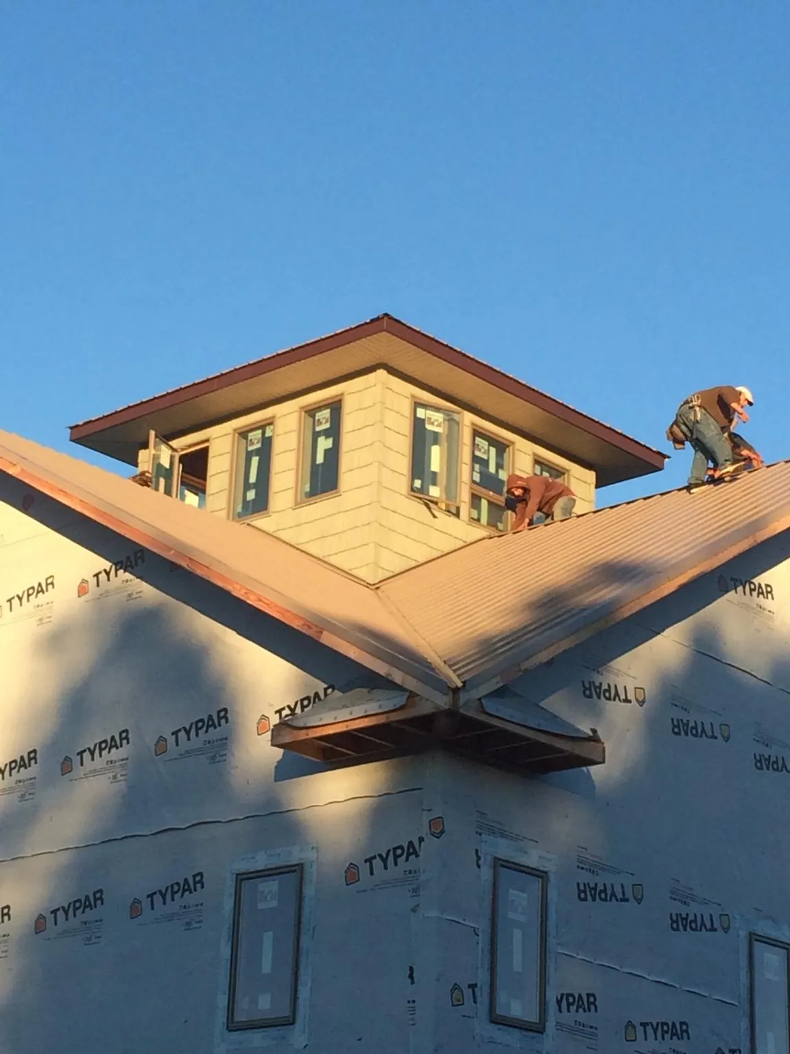 Roofers working around a rooftop cupola on a new metal roof at sunset — Roof Waterproofing in Woodland Hills by Roofing Brothers